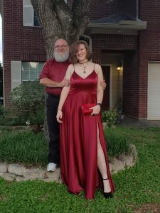 Me standing on a block behind my tall daughter in her prom dress